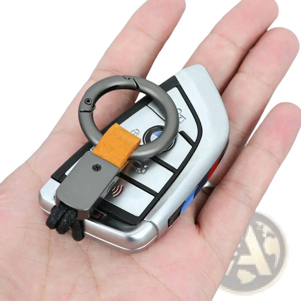Silver bmw key fob attached to a leather keychain lanyard with a matte black metal ring carabiner and orange strap