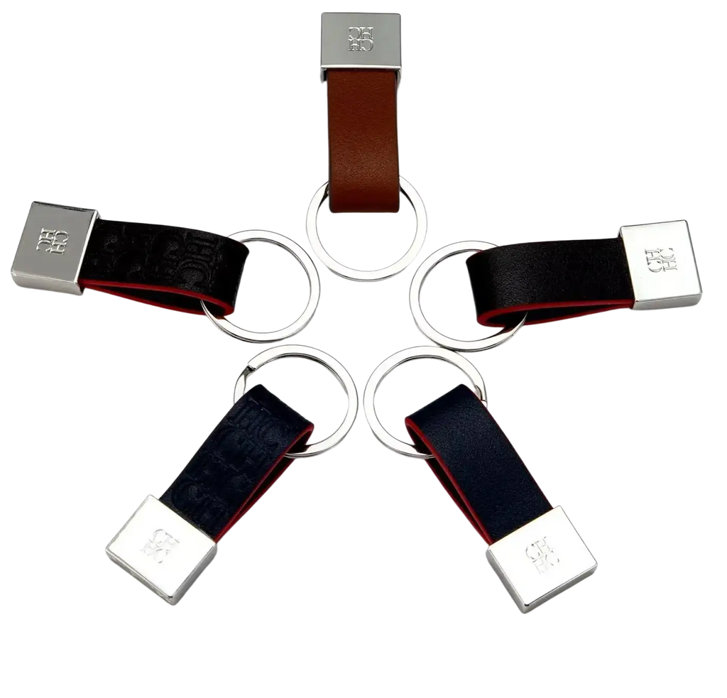 Leather keychain minimalist luggage accessory in brown and black leather with silver logo plate and circular ring attachments