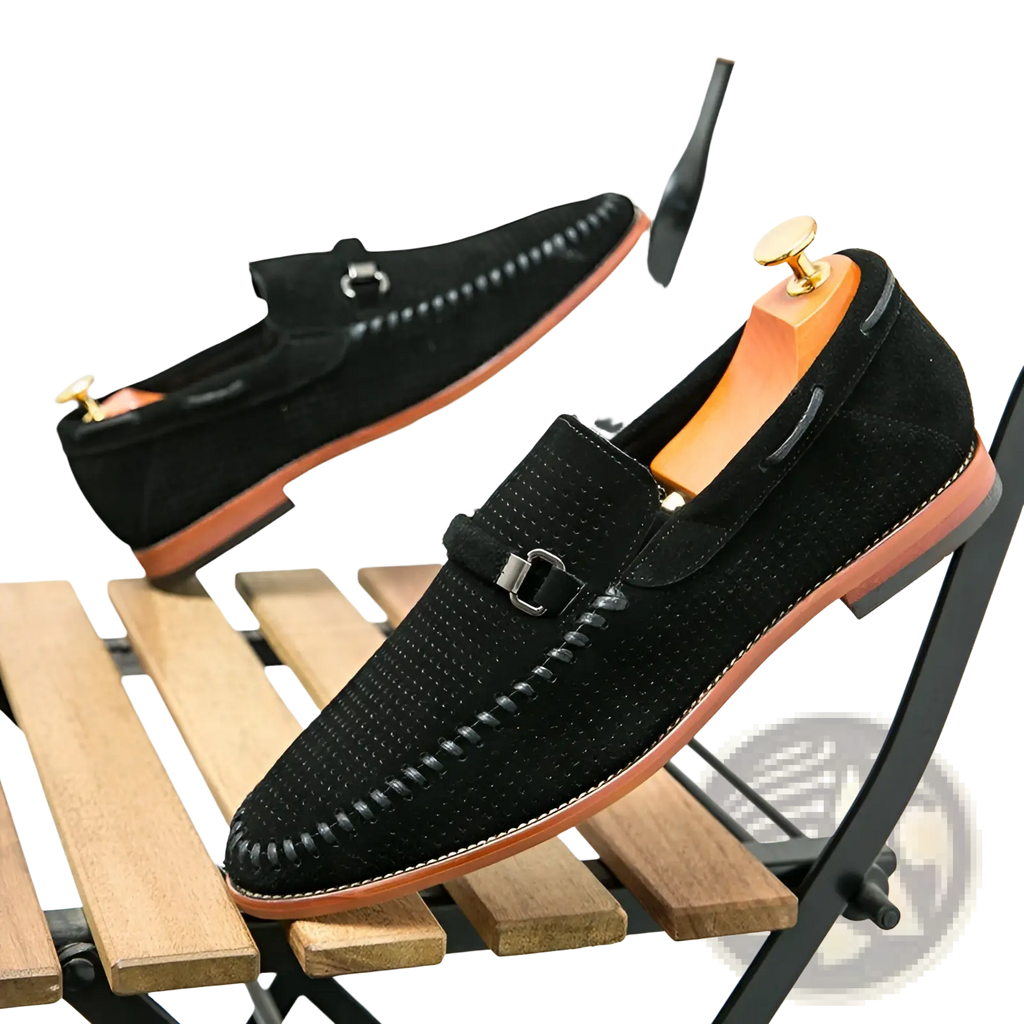 Black leather loafers with perforated suede texture, stitched detailing, and metallic buckle strap slip on shoes