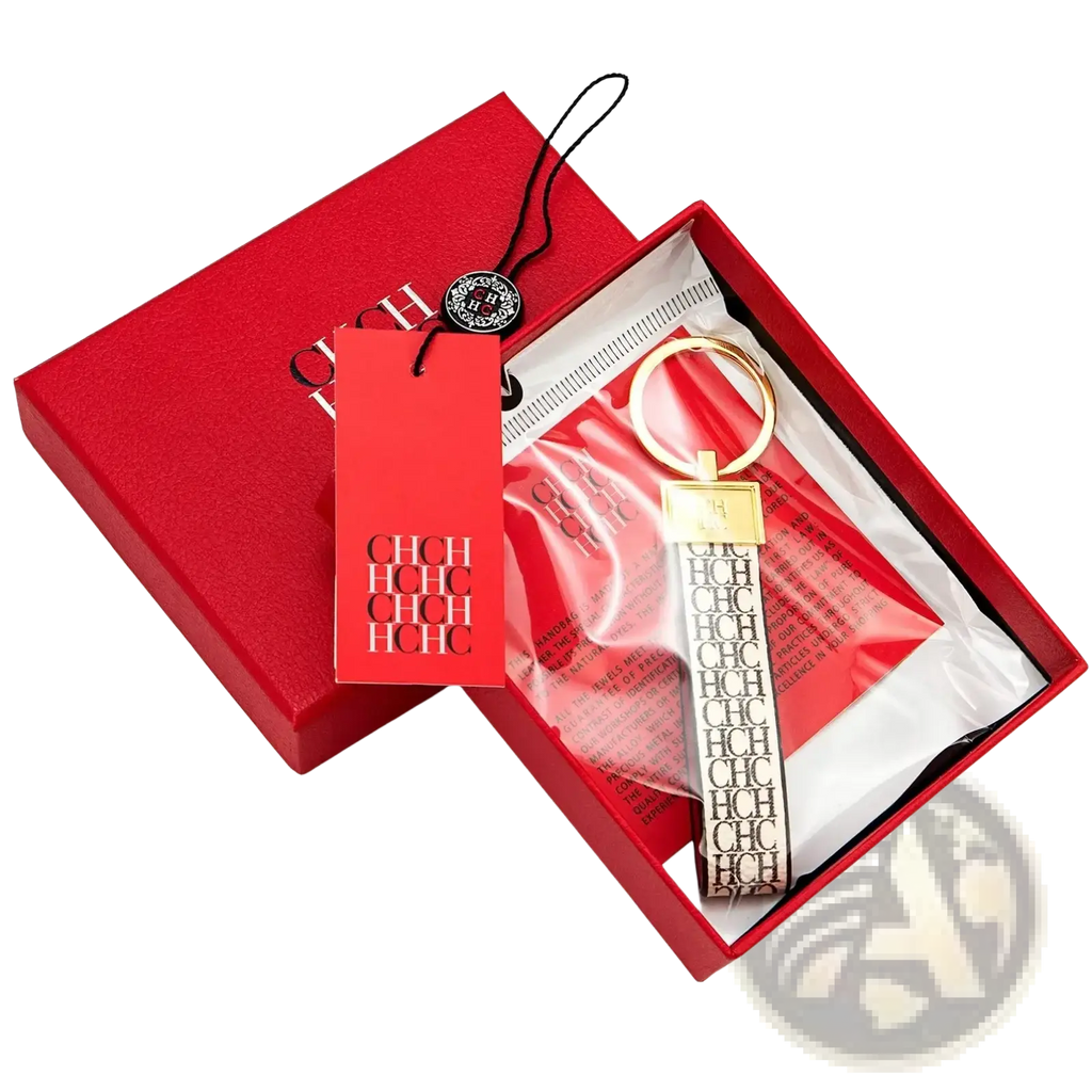 Gold-toned leather logo keychain with black and white ch strap in a red branded box for designer fashion accessory gift