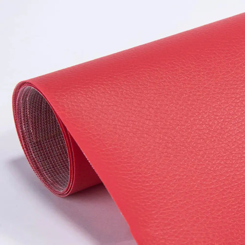 A roll of vibrant red self adhesive pu leather repair patch with a textured pebbled surface for furniture repair