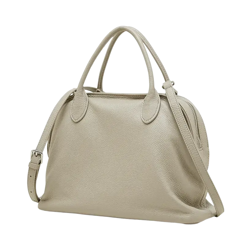 A soft beige leather shoulder bag with textured cowhide surface, dual handles, and adjustable strap from Guangdong province