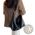 Black faux leather shoulder bag with gold-tone buckle and minimalist design for elegant everyday use
