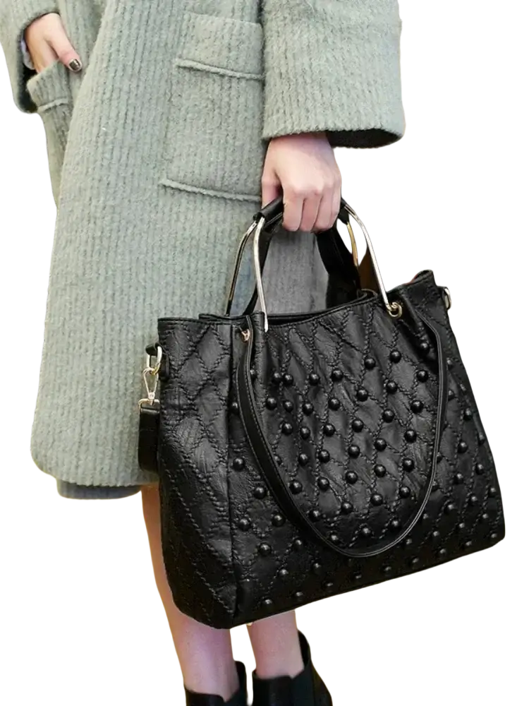 Black quilted leather shoulder bag with silver handles and pocket interior featuring black studs for elegant storage