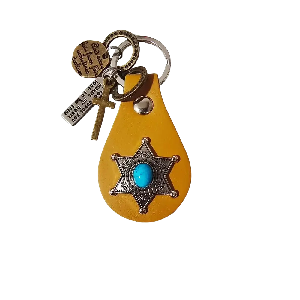 A yellow leather keychain featuring a silver star badge with turquoise stone and additional cross and metal tags charms