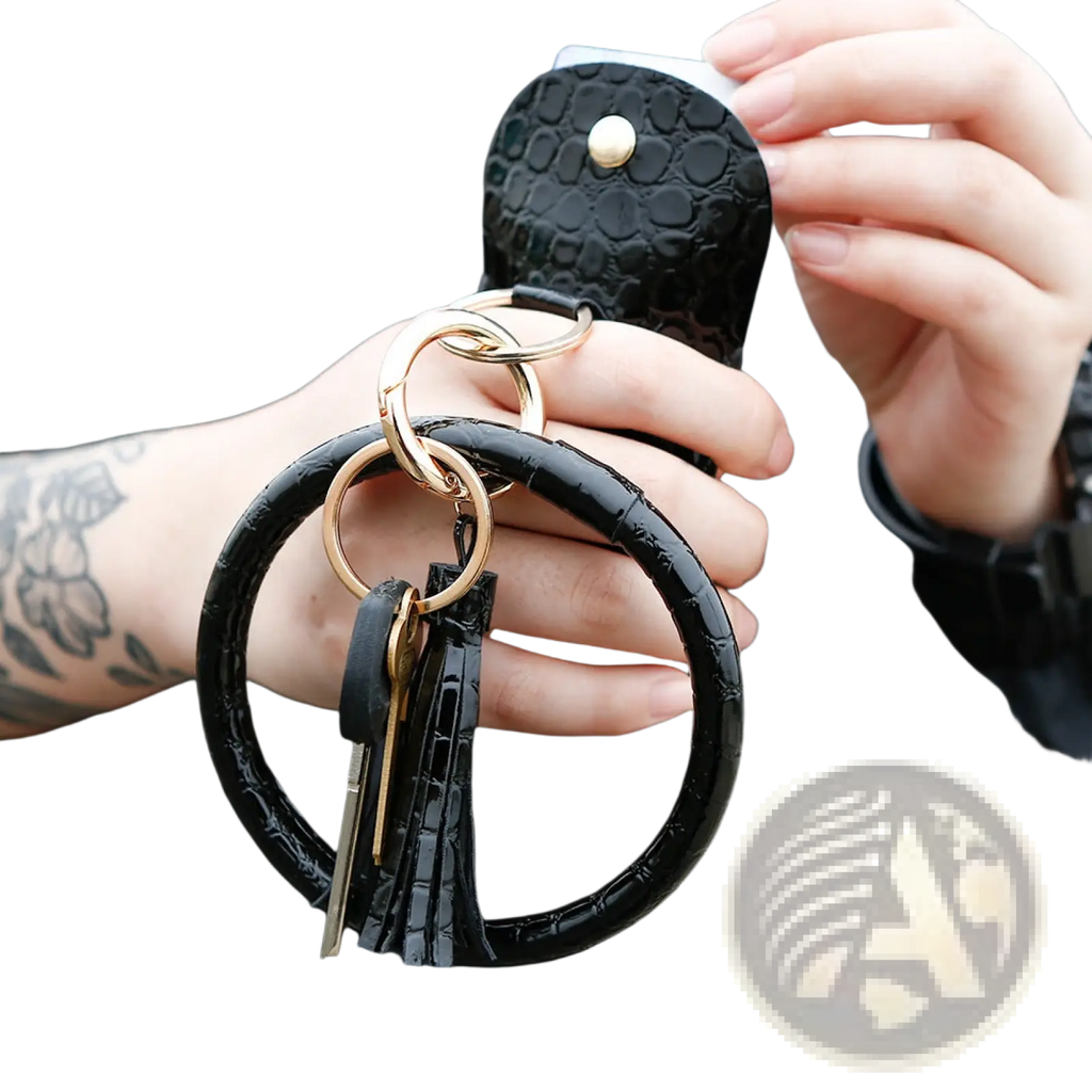 Black crocodile-textured leather wristlet keychain card holder with gold-toned rings and matching black tassel attached to wallet
