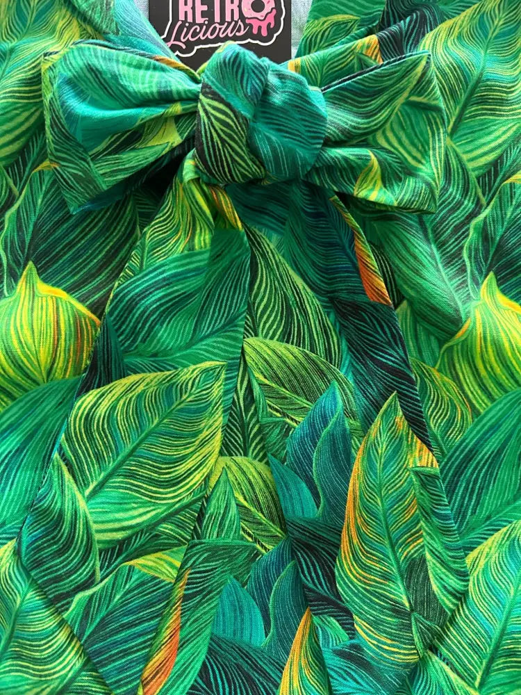 Tropical leaf print 1950s vintage cotton blouse with vibrant green fabric and a prominent bow tied at the top