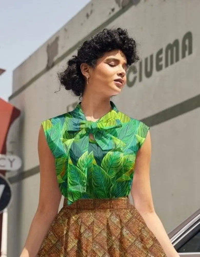 A vibrant green tropical leaf print 1950s vintage cotton sleeveless blouse with a bow at the neckline