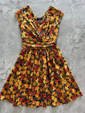 Greta autumn leaves cotton wrap dress with v-neckline gathered waist and red orange yellow leaf pattern on dark fabric