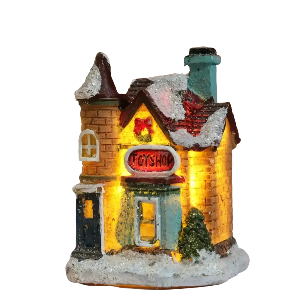 A warmly lit led christmas village toy shop with yellow brick facade snow-dusted roof and festive holiday decorations