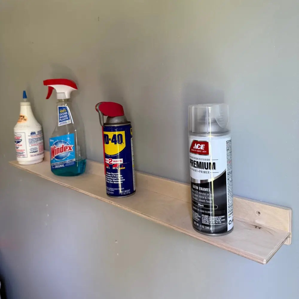 A blue and yellow wd-40 can with red cap placed on a white metal 36 inch garage ledge shelf and organizer bracket
