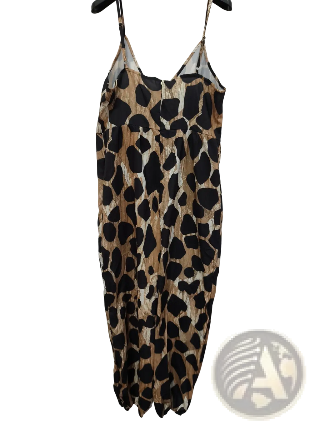 A black and tan leopard print spaghetti strap jumpsuit with a deep v neck hanging on a hanger