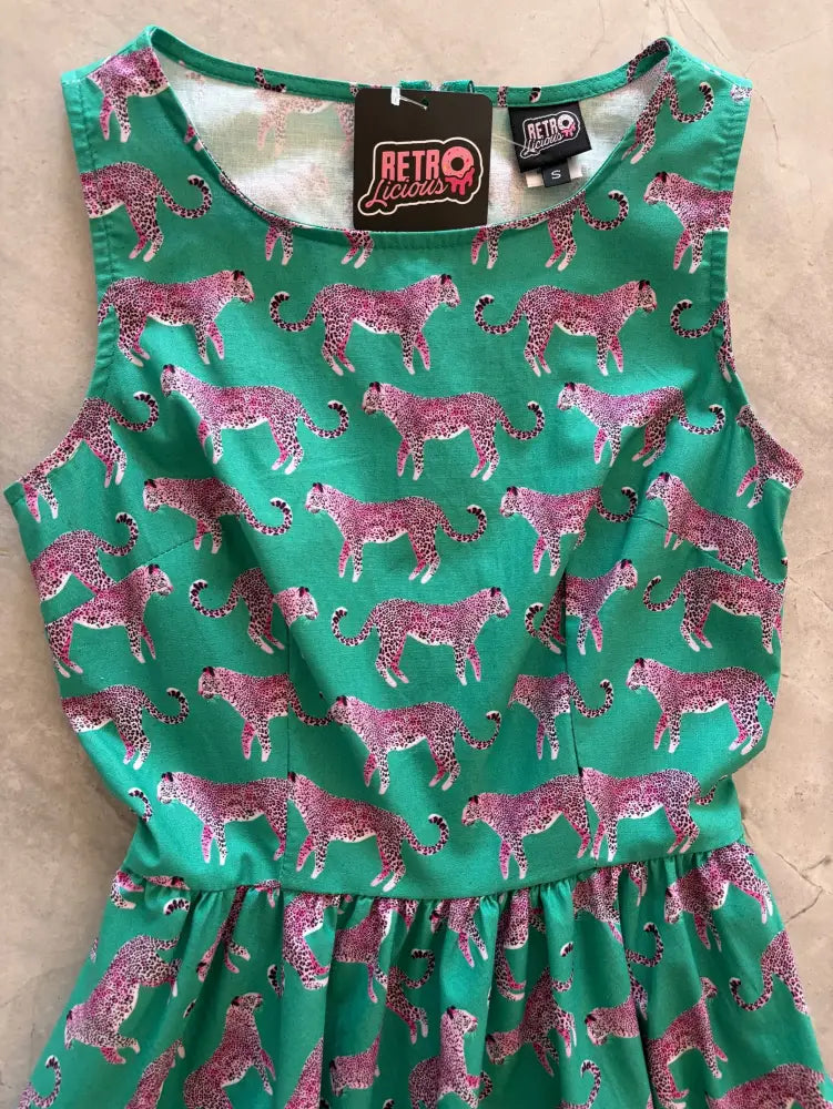 Vintage green cotton 1950s flare dress with a sleeveless design and repeating pink cheetah print pattern
