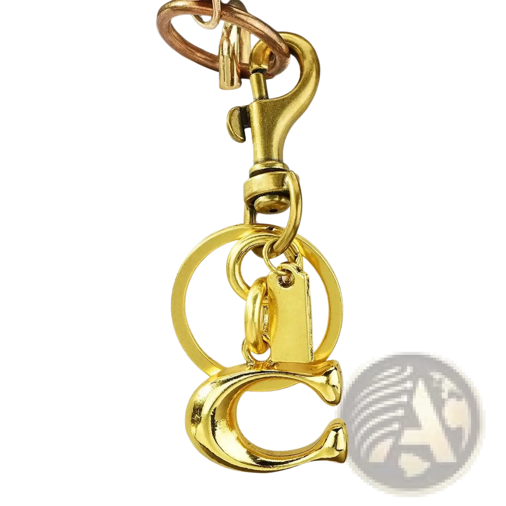 Gold-colored metal keychain with c initial charm and circular ring attached to white quilted leather bag