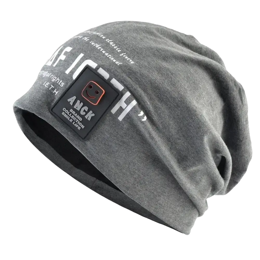 Gray textured beanie hat with white letter print and black anck patch featuring a smiling face logo for casual streetwear