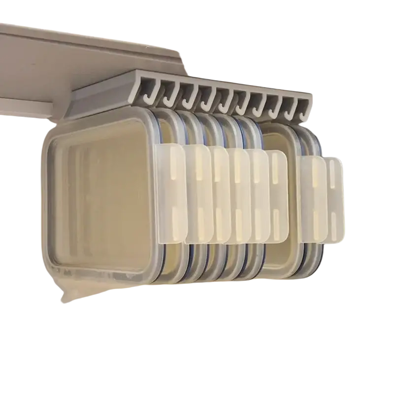 Gray plastic wall-mounted lid storage rack holding clear containers with blue and white lids for space saving organization