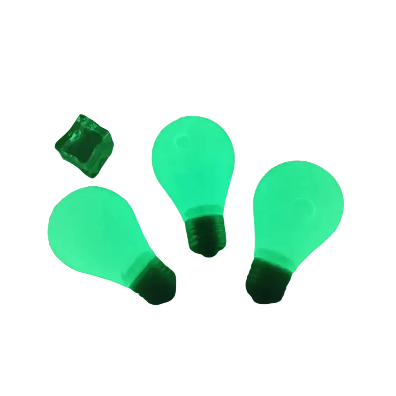 Three glowing green light bulb stress relief squeeze toys with black bases arranged on white surface with colorful cubes