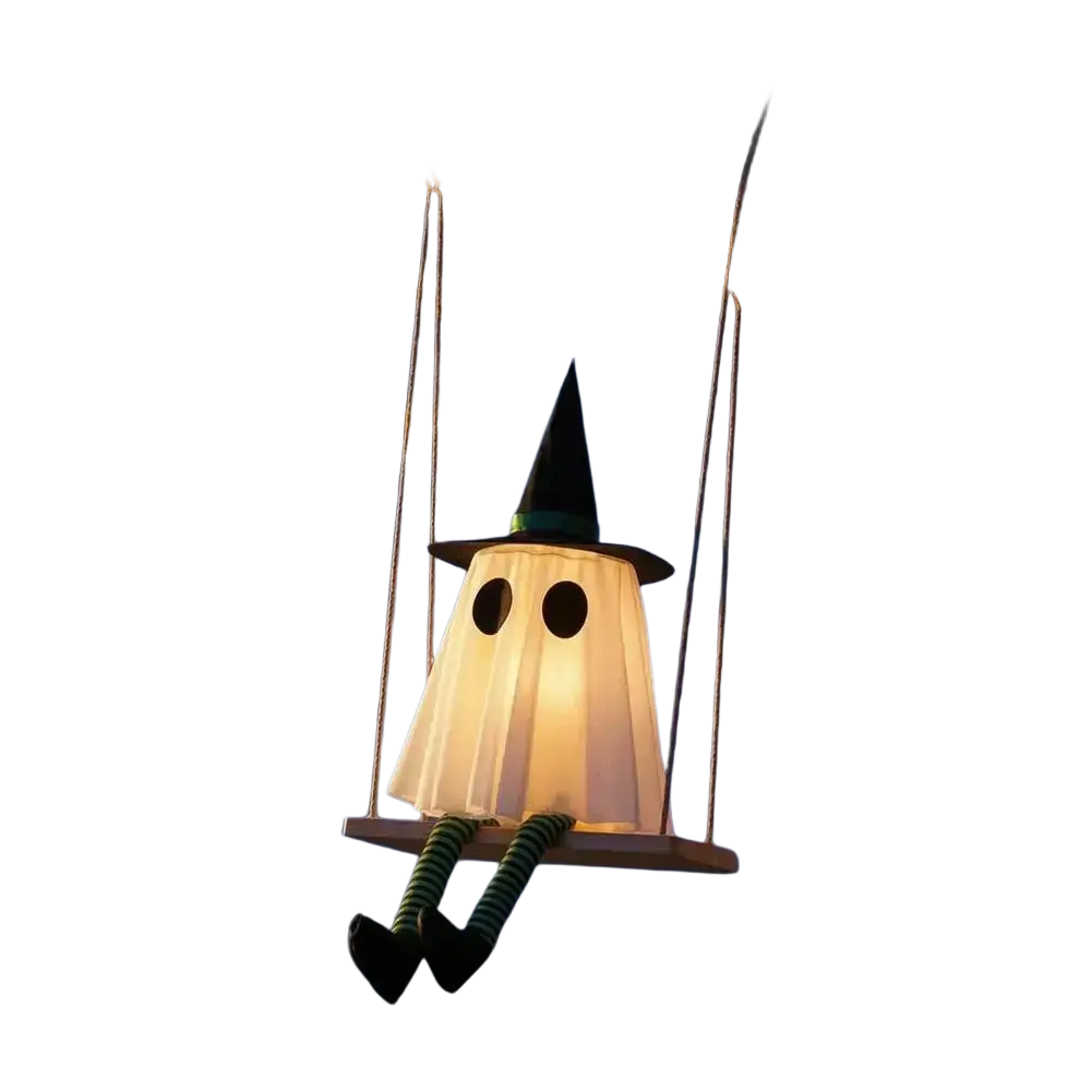A glowing white swing ghost decoration with a black witch hat and striped green legs hanging from a tree branch
