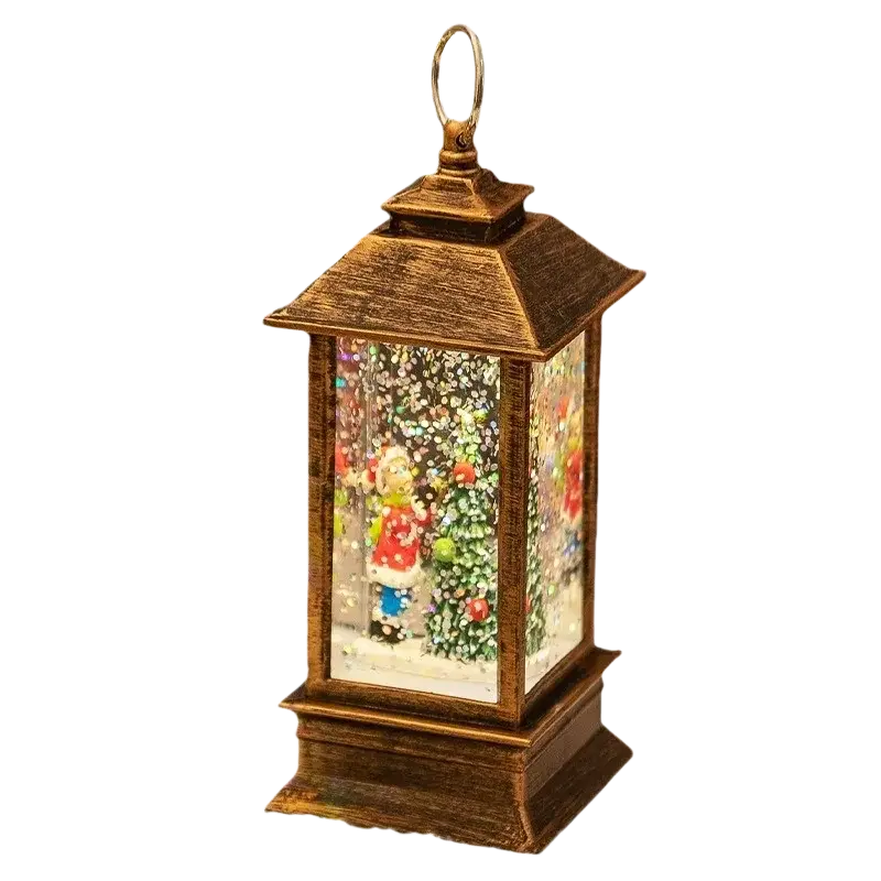 Antique brass finished lighted bronze Christmas snow globe lantern with miniature snowfall and Santa beside a decorated tree