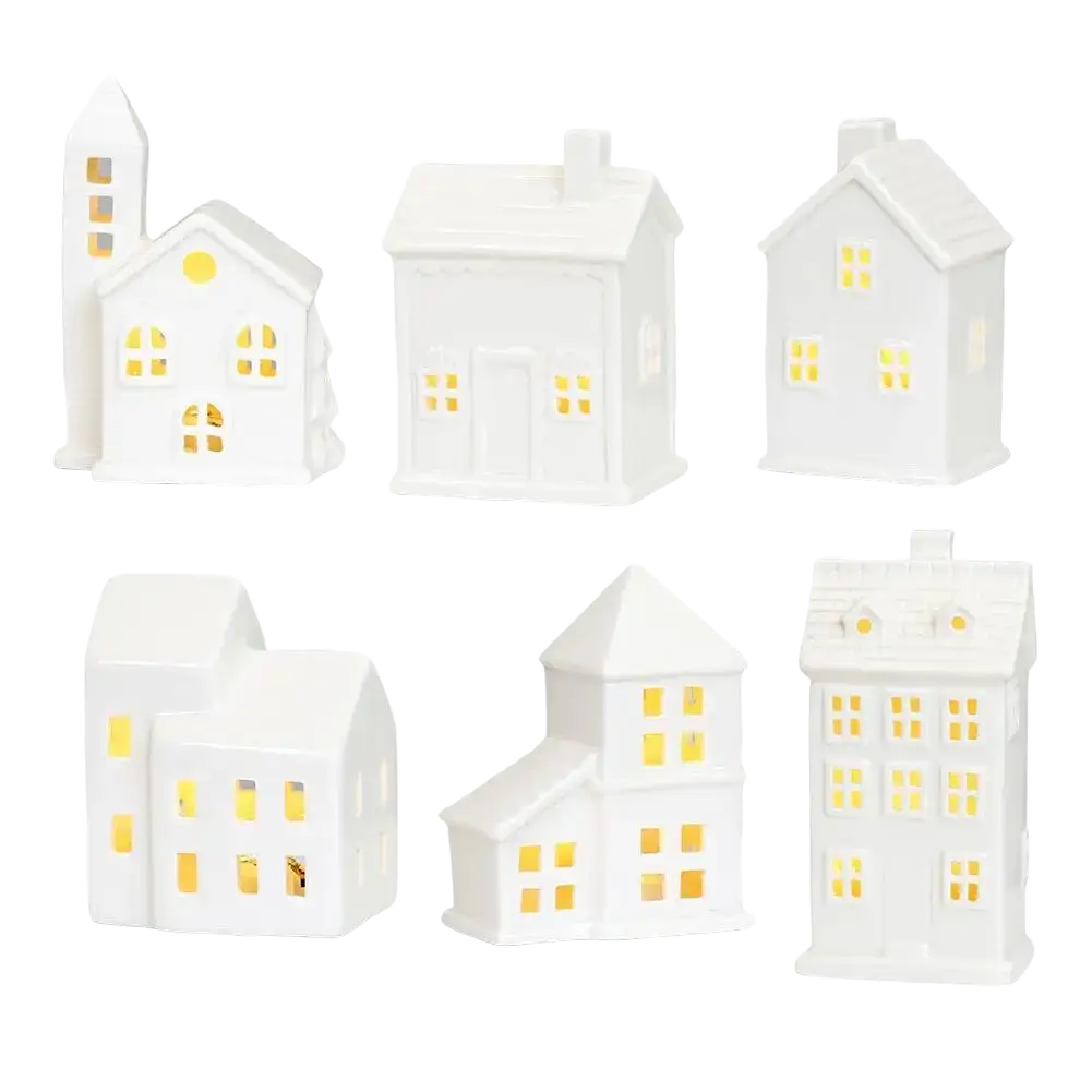White ceramic christmas village houses with glowing yellow led lights creating an enchanting winter wonderland scene