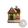 Lighted Christmas village house ornament with brown brick facade, green door, blue glass windows, and snow-dusted roof