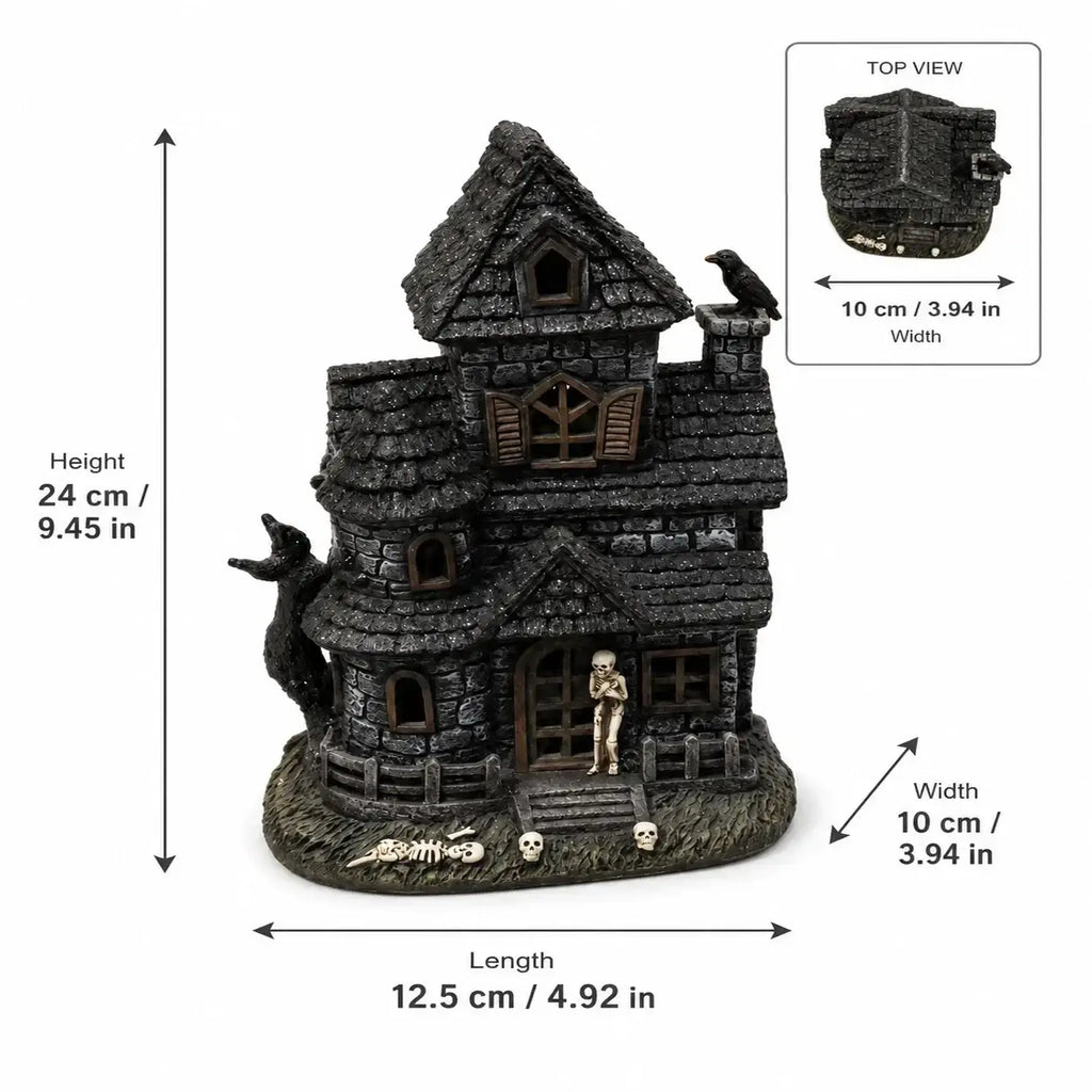 Dark gray lighted haunted house resin figurine with crooked roof, skeleton at door, and skulls around base