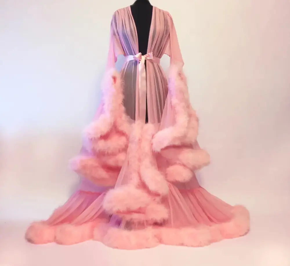 A flowing pink sheer bridal robe with voluminous fluffy tulle trim and a matching bow at the waist