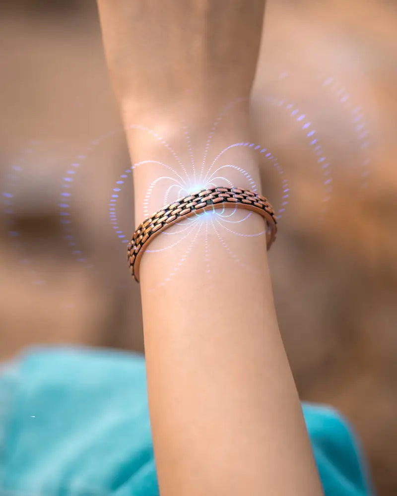 A copper-toned link chain magnetic therapy cuff bracelet with a woven design and subtle glowing energy lines