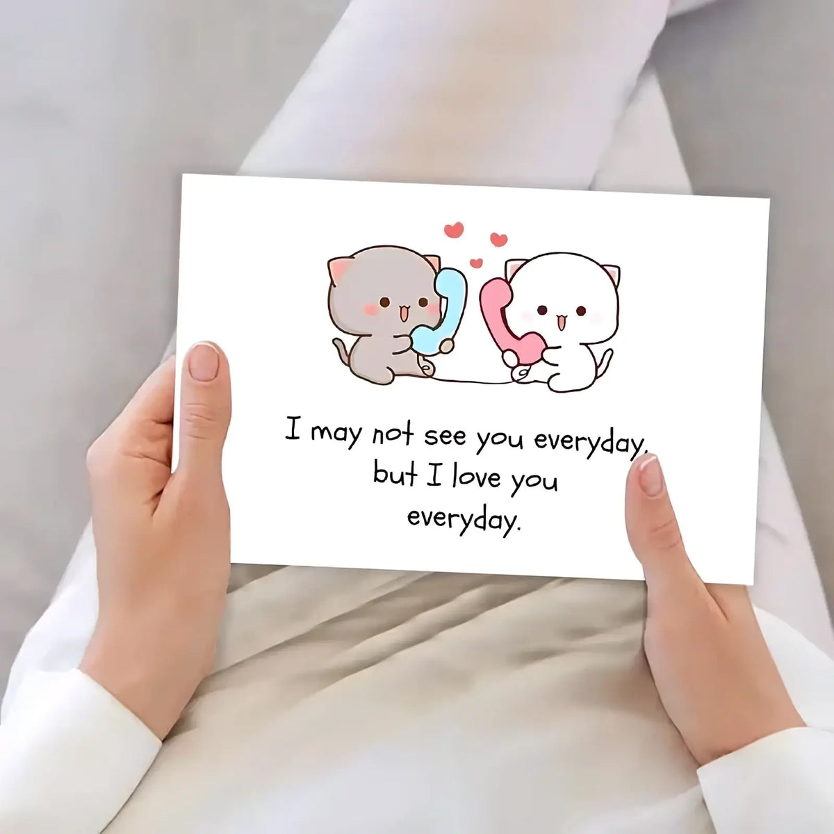 A white rectangular long distance cat couple greeting card with cartoon cats holding colorful phones and loving text