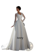 Ivory wedding dress with long sheer lace sleeves and a fitted bodice featuring a v neck lace back design