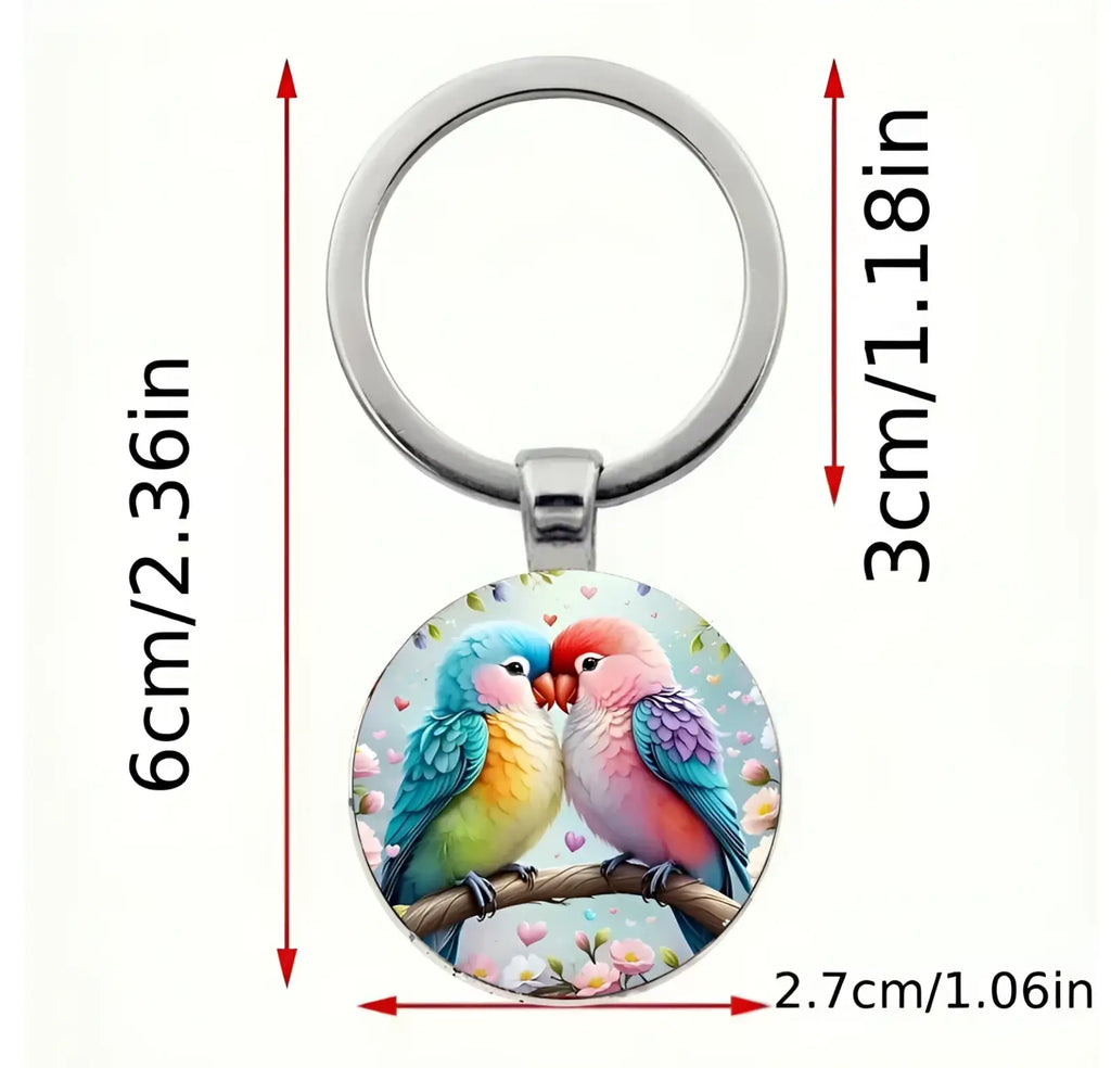 A lovebird keychain featuring a colorful illustration under a clear glass dome with a silver metal ring