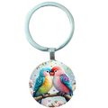 A round colorful glass dome lovebird keychain featuring two affectionate birds on a floral branch with hearts