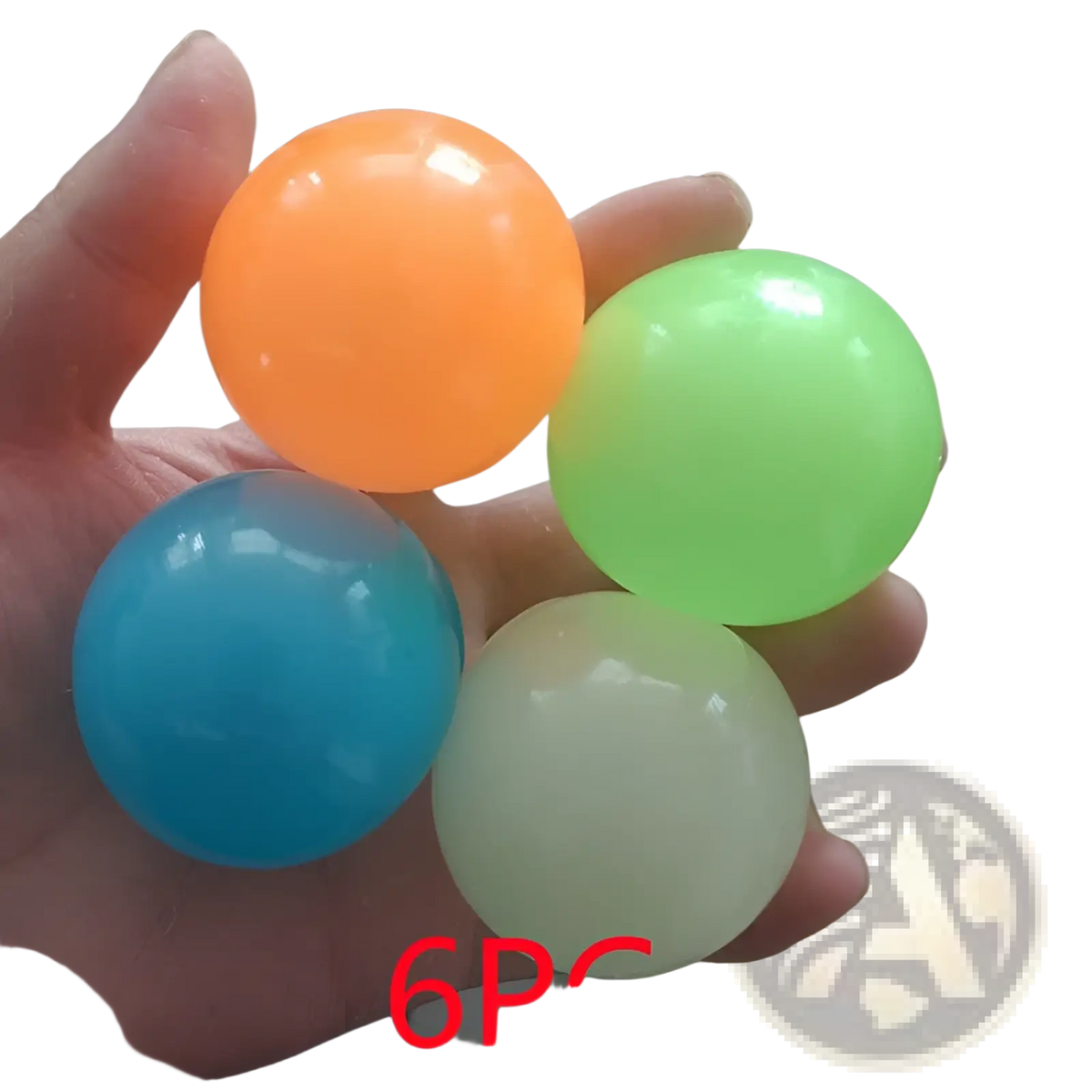 A hand holds four colorful translucent luminous sticky wall balls glow in the dark squeeze toys in orange green blue and pale yellow