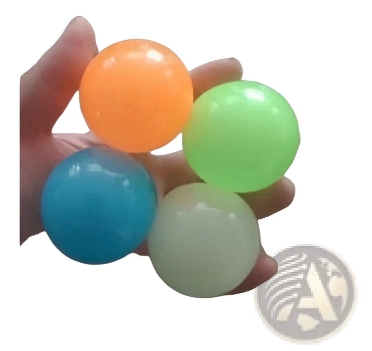 A hand holds four translucent glossy luminous sticky wall balls in orange green blue and white glow in the dark squeeze toys