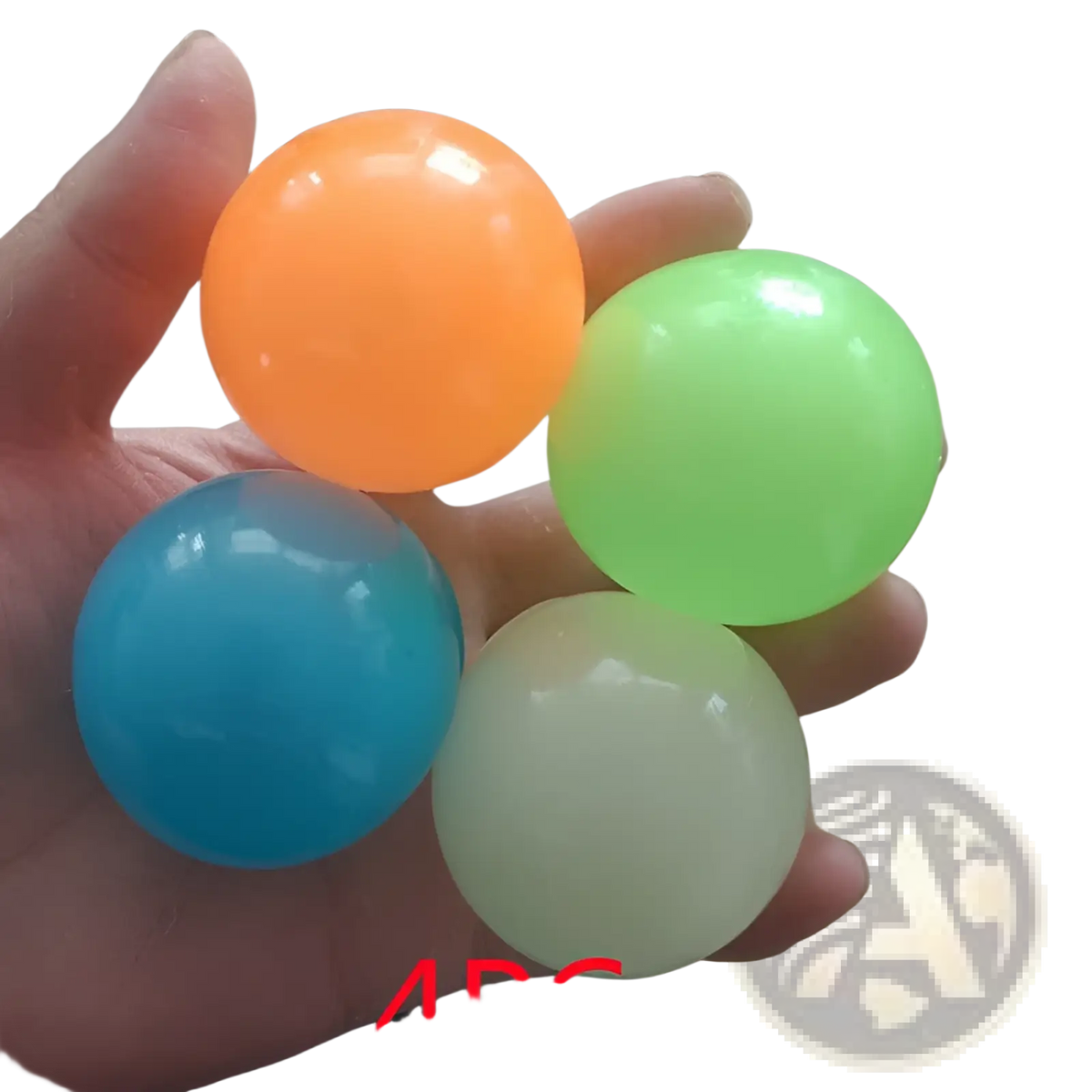 A hand holds four colorful translucent luminous sticky wall balls glow in the dark squeeze toys in vibrant hues