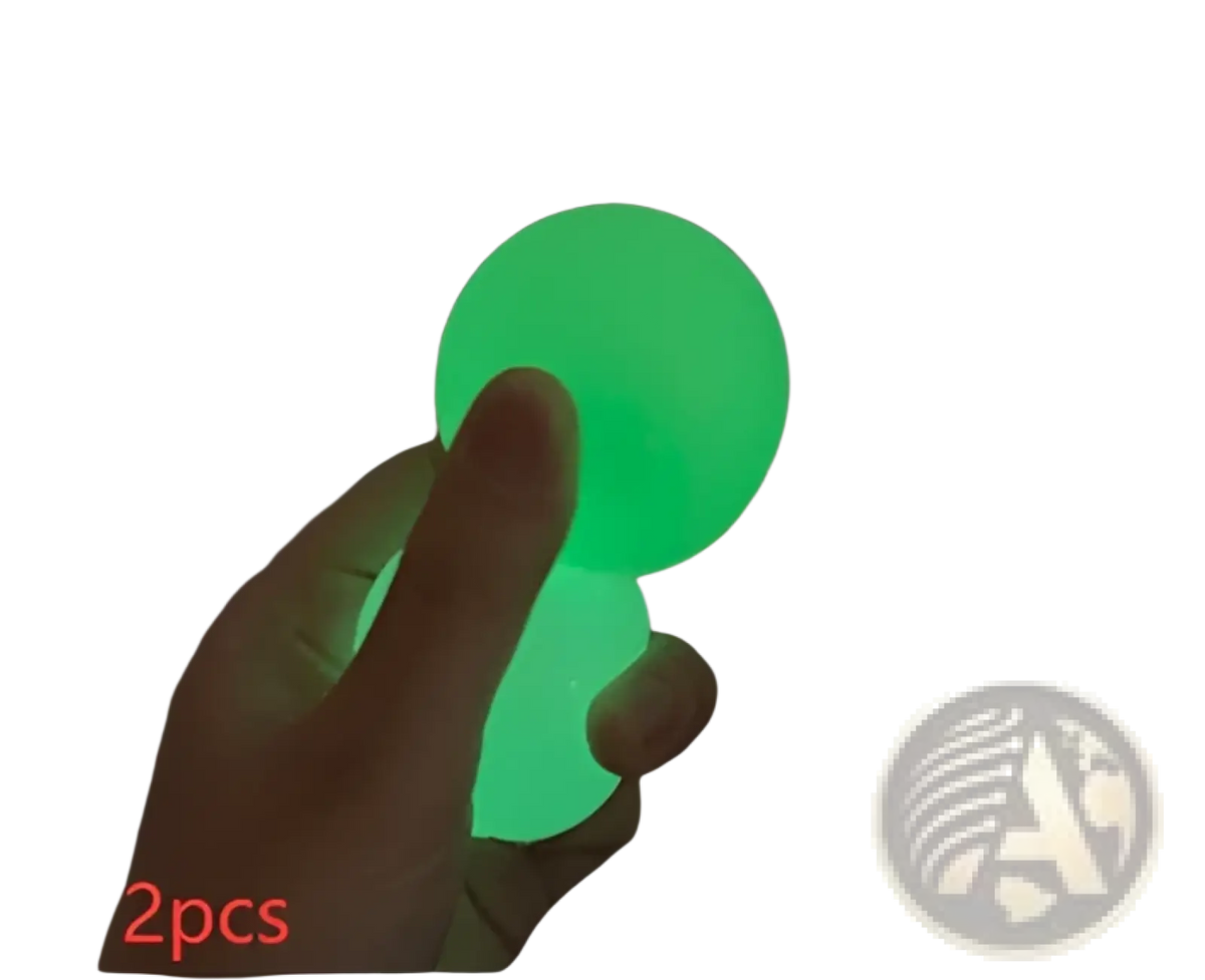 A hand holds two glowing green translucent luminous sticky wall balls glow in the dark squeeze toys
