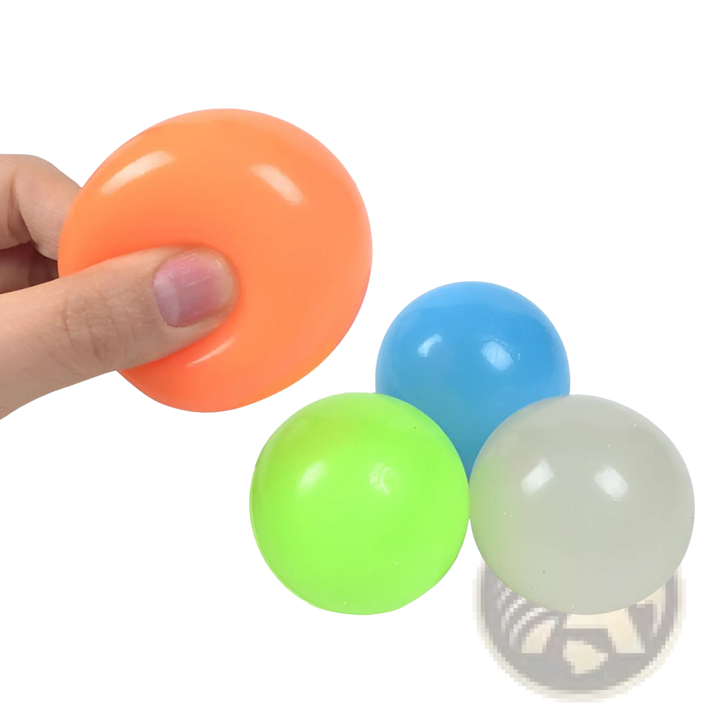 Orange glossy plastic luminous sticky wall ball glow in the dark squeeze toy held in hand for stress relief