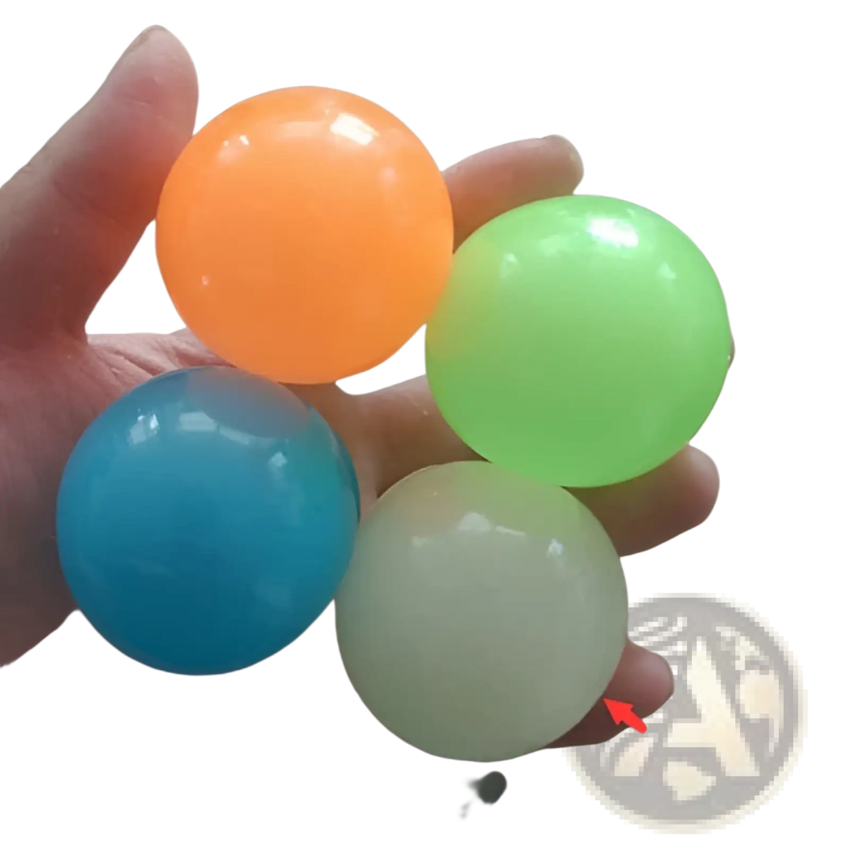 A hand holds four translucent luminous sticky wall balls glow in the dark squeeze toy in orange green blue and pale yellow