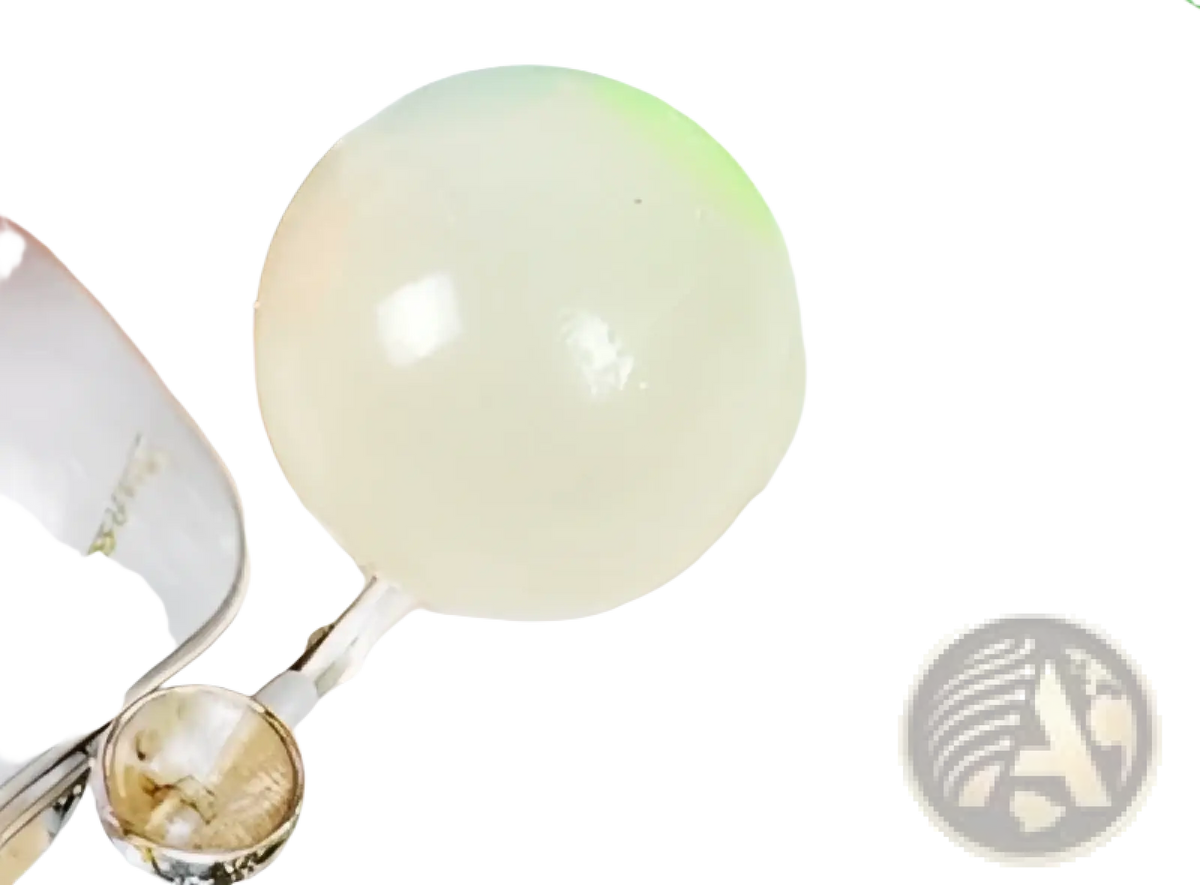 A translucent pale green spherical luminous sticky wall ball glow in the dark stress squeeze toy with a smooth surface