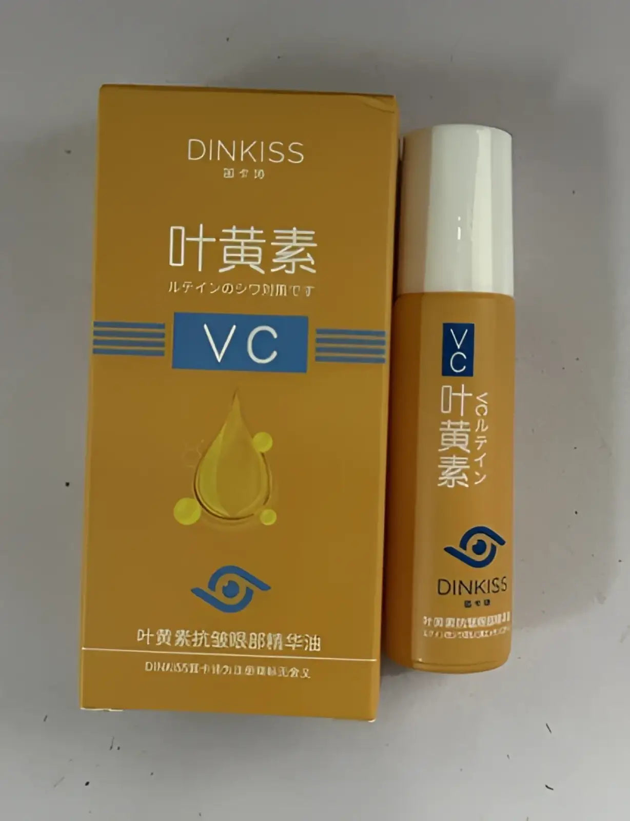 Orange-tinted dinkiss vc eye serum bottle with white cap and matching droplet design box for hydrating lutein eye oil