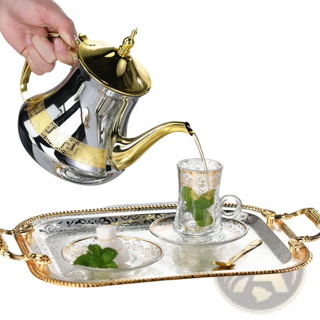 Luxury rectangle serving tray with gold handles holding a shiny silver and gold ornate teapot pouring tea into a matching cup