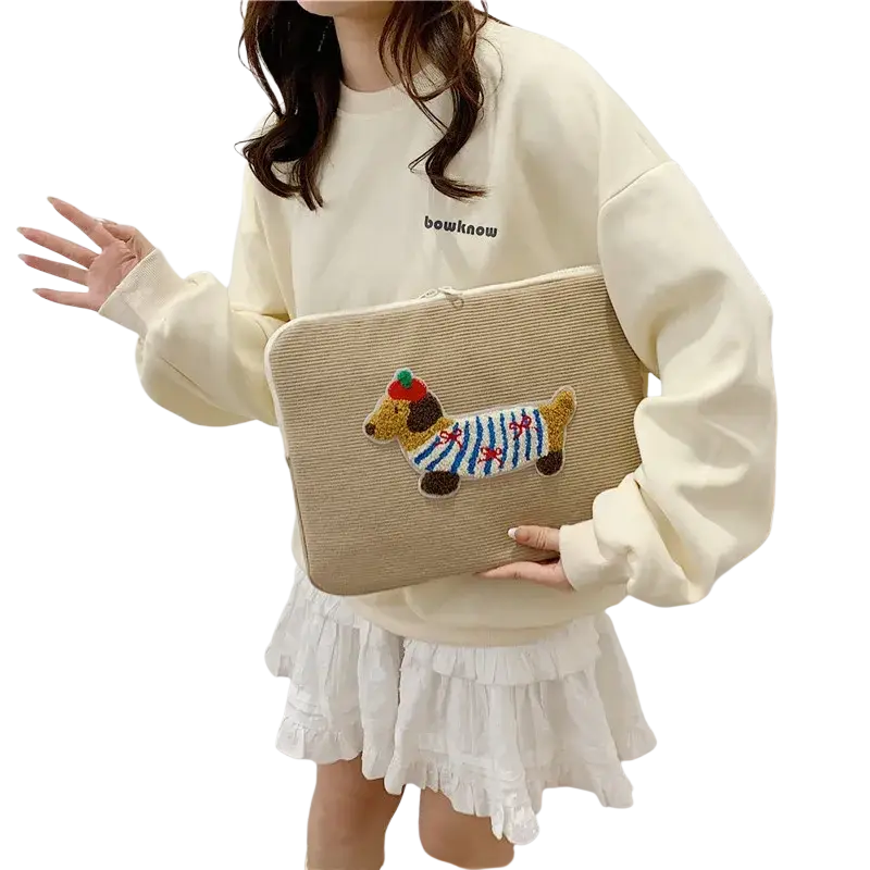 Beige corduroy macbook pro laptop sleeve with colorful embroidered dachshund wearing blue striped sweater and green hat