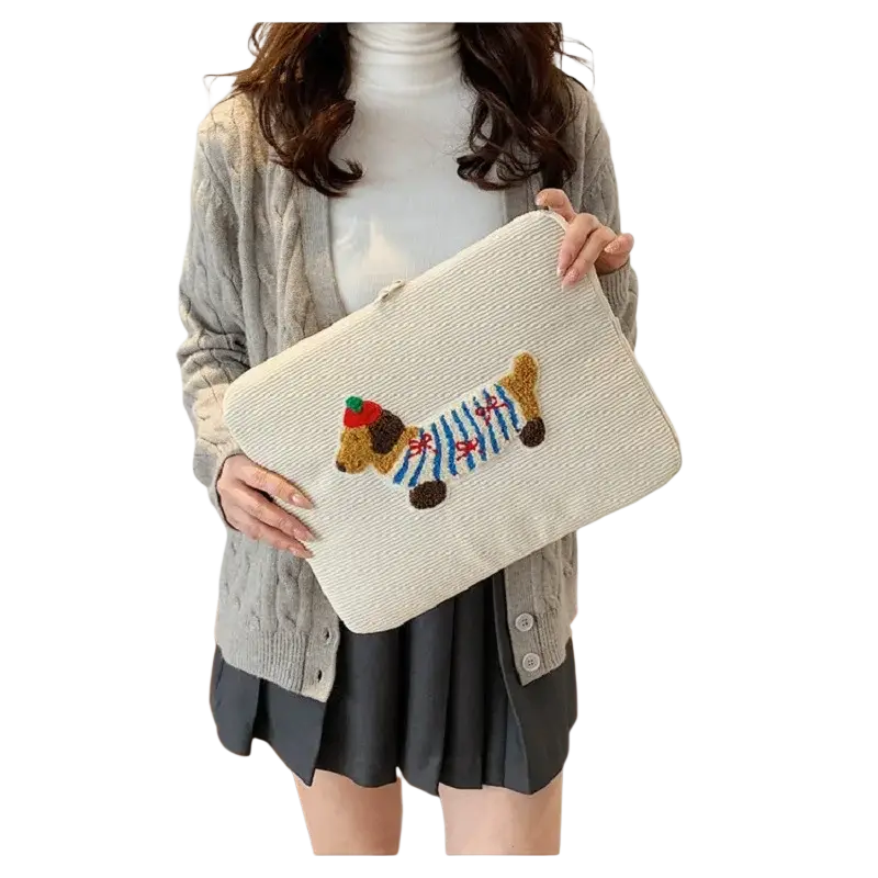 Beige corduroy macbook pro laptop sleeve featuring an embroidered dachshund in brown and blue striped attire with red hat