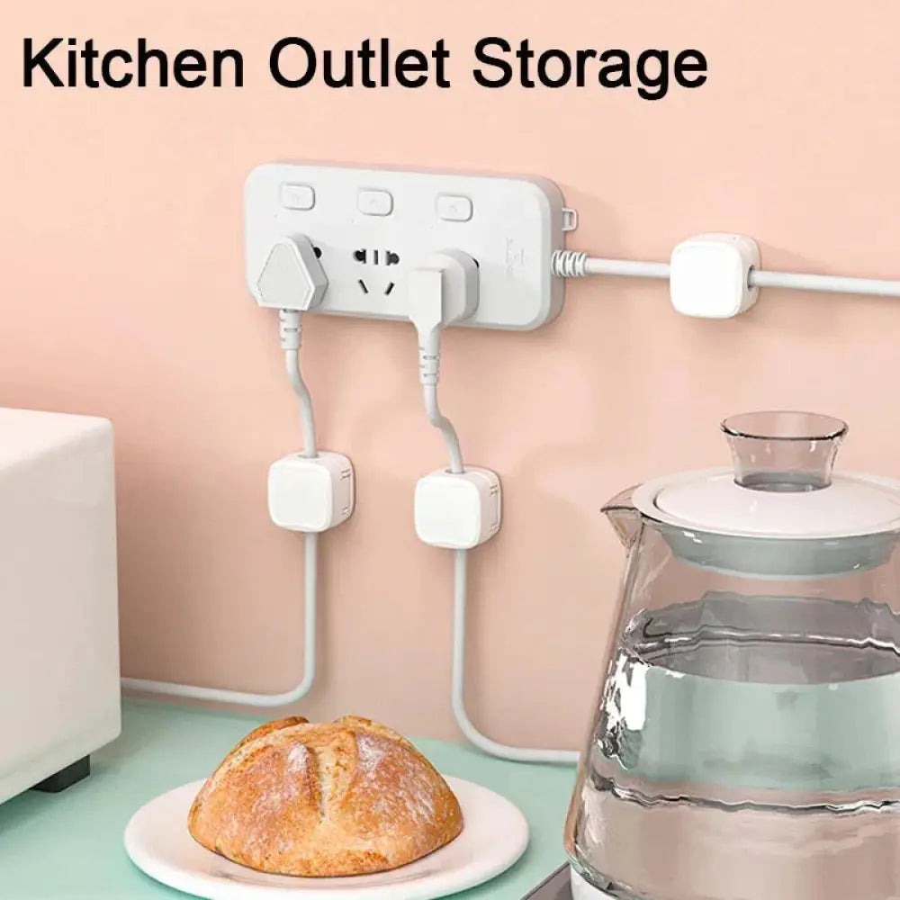 White magnetic square under desk cable organizer storing multiple plugs and cords neatly in a kitchen outlet area