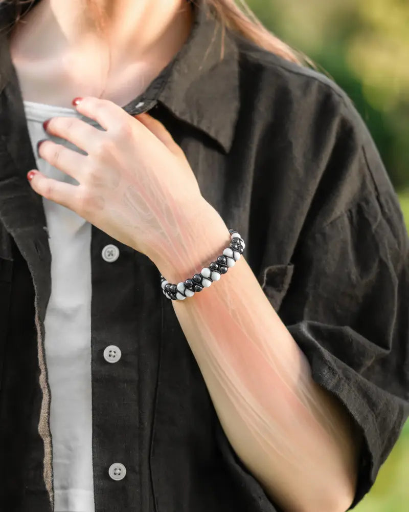A black and white beaded moonstone and magnetic hematite bracelet worn on a wrist showcasing its design and quality