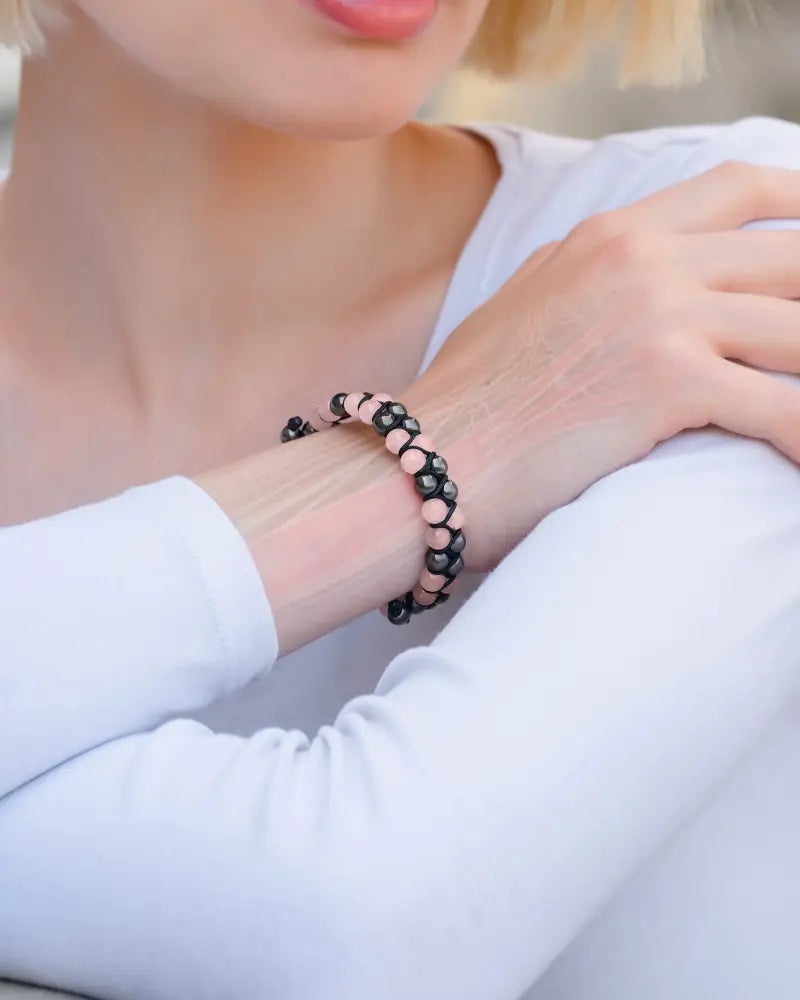 A delicate rose quartz and magnetic hematite beaded bracelet with alternating black and soft pink beads worn on a wrist