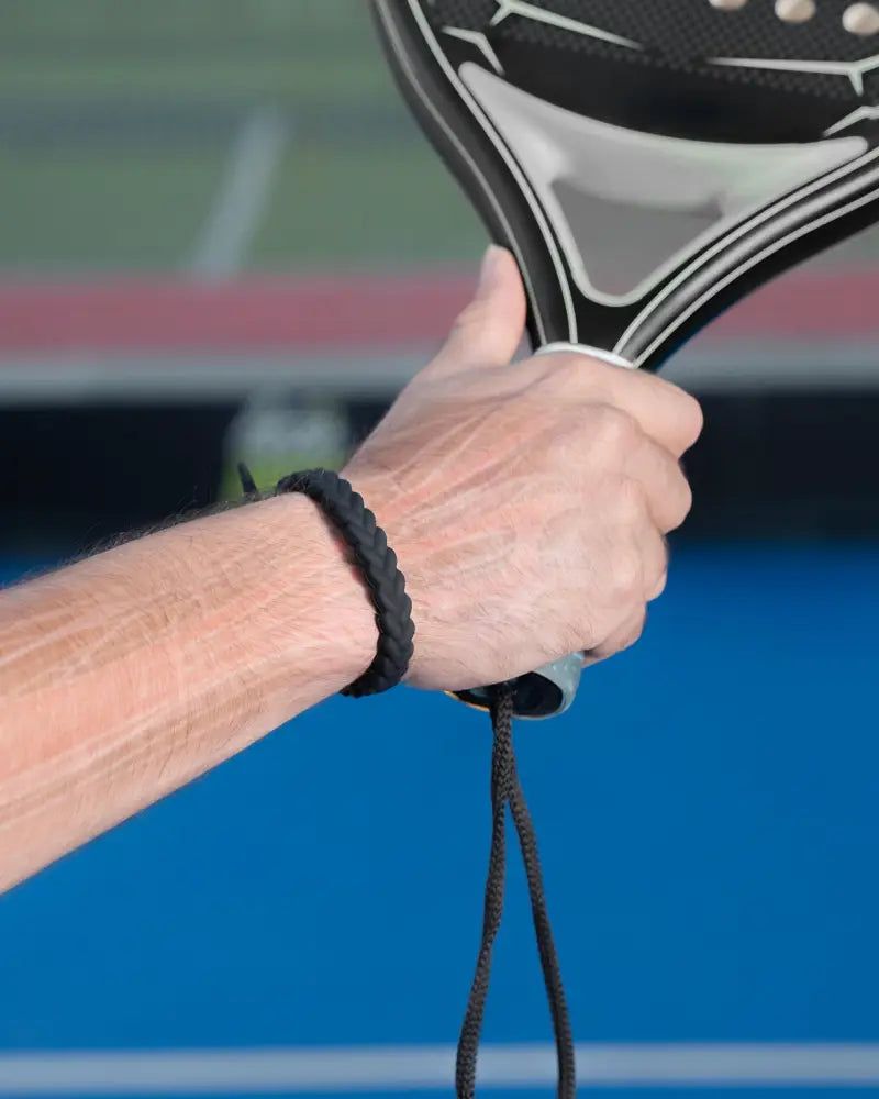 Black braided silicone magnetic golf bracelet from magnetrx worn on hand gripping a paddle