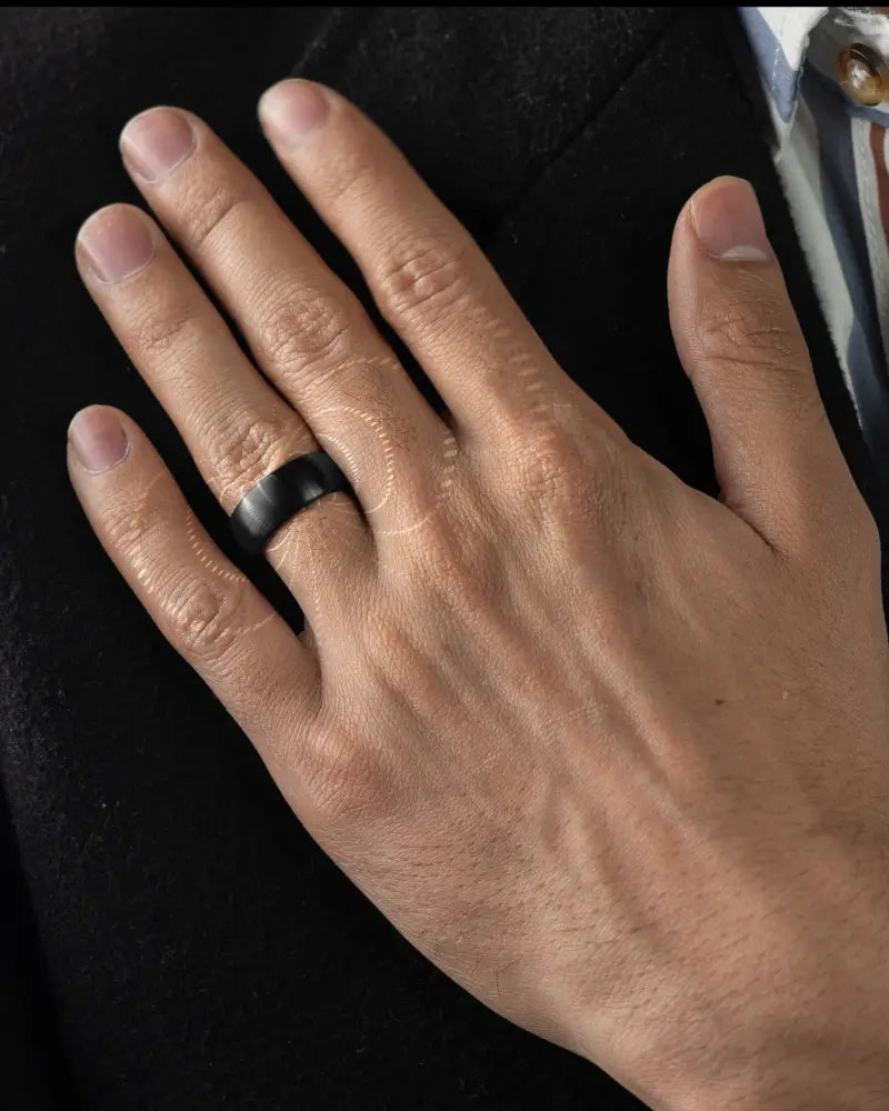 Brushed black stainless steel neodymium magnetic therapy ring with smooth matte ceramic finish worn on middle finger