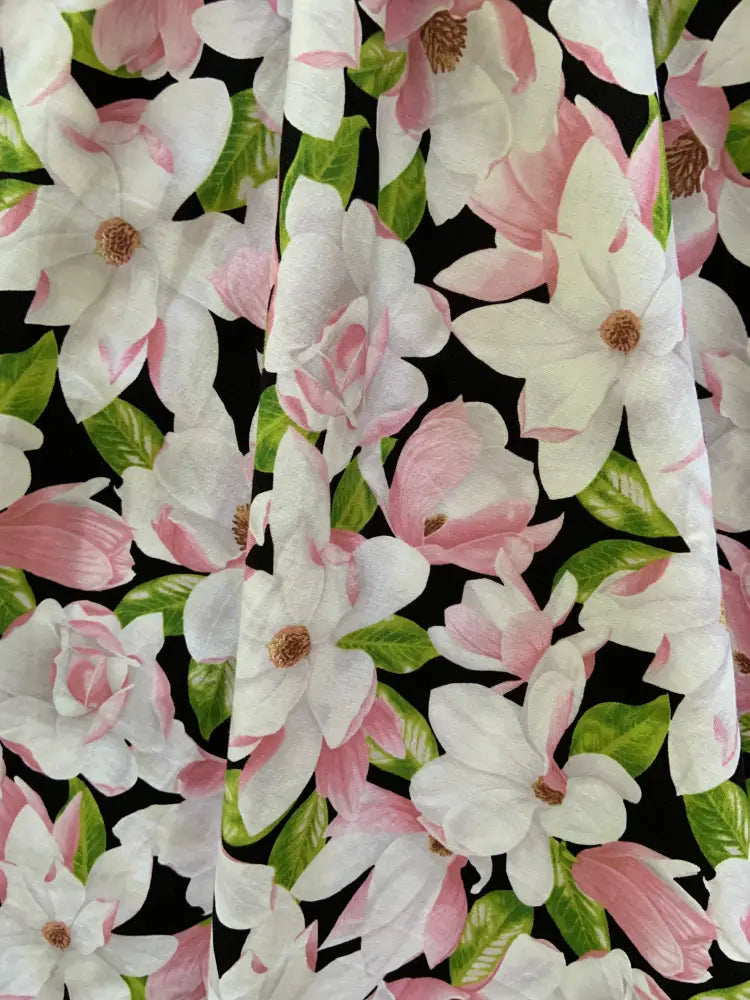 Black cotton midi dress with pockets featuring a repeating pattern of white and pink magnolia flowers with green leaves