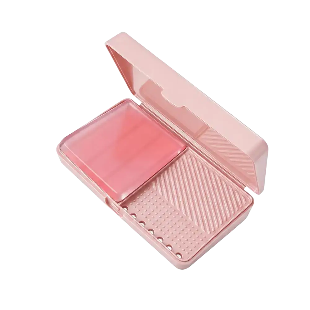 Pink plastic makeup brush cleaning soap box with clear lid and textured interior compartments for easy use